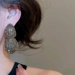 Close-up of vintage teardrop earrings with dark rhinestones on a female model