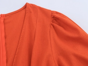 Detail of V-neck orange cotton linen dress showing puffed sleeves and invisible zipper
