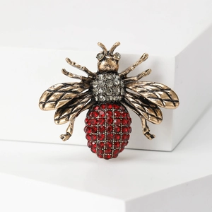 Detailed macro shot of vintage bronze bee brooch with red and clear inlaid crystals