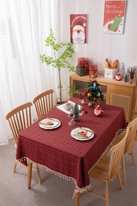 Close-up of red plaid Christmas tablecloth featuring beige fringe tassels and festive gold yarn