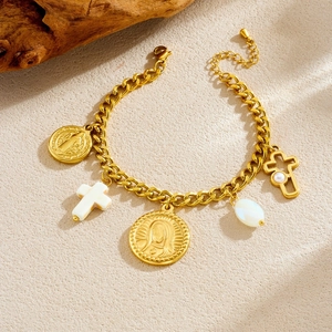 Gold-plated religious coin and cross pearl charm necklace on rustic stone background