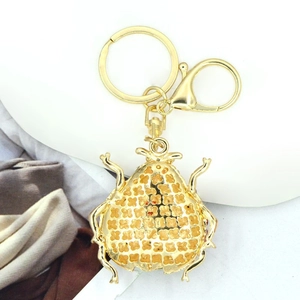 Detail of the golden beetle keychain showing hollow flower patterns on the back part