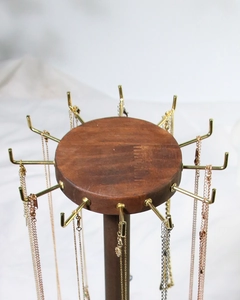 Detail of wooden jewelry display stand with rotating gold metal hooks for necklaces