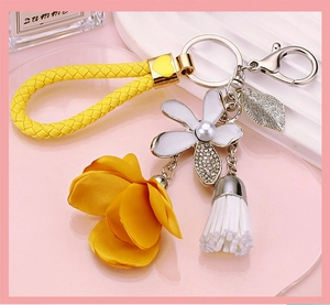 Detail view of yellow silk flower keychain with white enamel charm and pearl accents