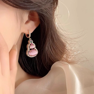Close-up of pink cat eye gourd earrings with 14k gold plating and zircon inlay on model