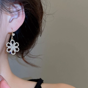Detail of flower shaped gold earring with rhinestones on model side profile view