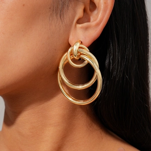 Detail shot of golden multi-layer nested geometric round hoop earrings on model