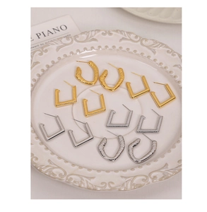 Macro view of textured 18K gold and silver plated geometric earrings on a tray