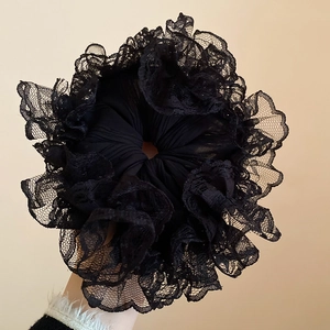 Gros plan d'un grand chouchou en dentelle noire montrant les détails de la broderie