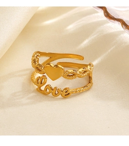Macro shot of gold heart ring with love lettering on soft beige silk fabric background