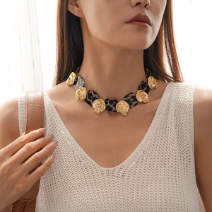 Close-up of a leopard print resin necklace with golden spiral shell metal details