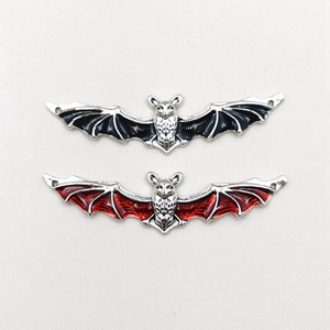 Detailed view of silver bat charms with red and black enamel wings for DIY jewelry making