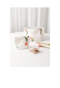 Close-up of elegant floral tulip embroidery on premium textured fabric cosmetic bags