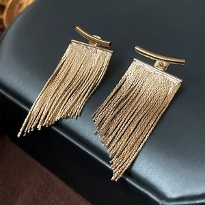 Detail of gold metal tassel earrings with curved bar studs on black leather display