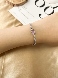 Close-up of a silver bracelet with a pink oval zircon stone on a woman's wrist