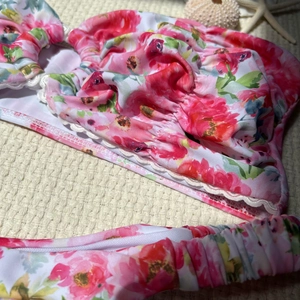 Close-up of pink floral bikini fabric featuring delicate white lace trim and ruffled edges