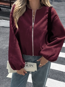 Detail view of burgundy oversized wool jacket with silver zipper and puffy sleeves on street