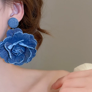 Detailed macro view of retro denim fabric rose earrings with fringe texture