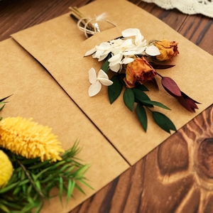 Detail of vintage kraft paper card with bouquet of dried roses and white petals