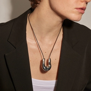 Minimalist irregular U-shaped polished silver pendant necklace with black cord on model