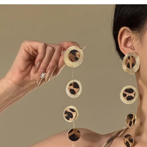 Detail of long leopard print tassel earrings with textured golden circles on model