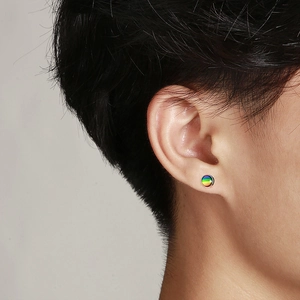 Close-up of a rainbow geometric round stud earring on a male ear in a street style