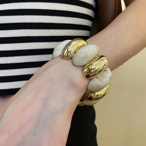 Detailed close-up of acrylic marble resin beads and golden metal beads on wrist