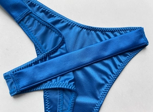 Detail of blue satin thong showing premium stitching and gradient rhinestone strap texture