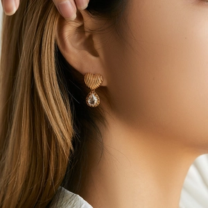 Close-up of golden heart and water drop crystal earring worn on female ear