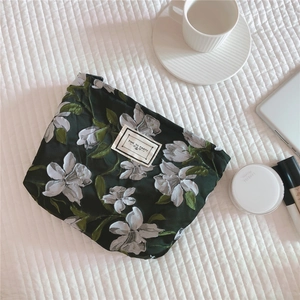 Detail view of dark green jacquard floral canvas clutch with 'Time to Party' woven label