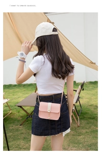 Close-up of pink and white crossbody bag with pearl pendants in outdoor setting