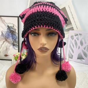 Close-up of pink and black striped knit cat ear hat with pom-pom tassels and texture