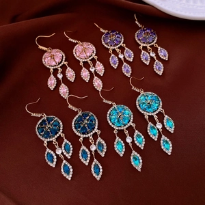 Detail of bohemian tassel earrings in pink, purple, and blue stones on velvet