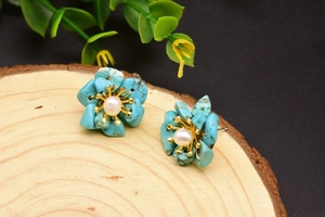 Macro view of flower stud earrings featuring blue petals and a white central pearl