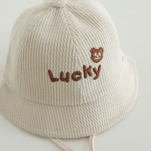 Gros plan détaillé du chapeau de soleil en velours beige pour bébé avec broderie ours