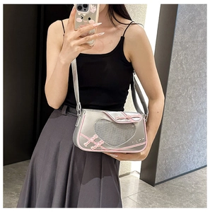 Close-up of heart-shaped mesh window with pink lace-up bows on silver metallic bag