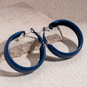 Boucles d'oreilles créoles géométriques larges bleu marine sur une surface en pierre