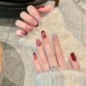 Detailed close-up of wine red cat-eye press-on nails with champagne gold glitter accents