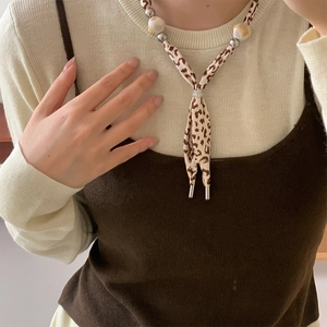 Detail of silk scarf leopard print necklace with marble beads and metallic finish