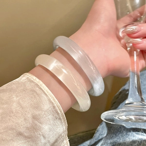 Minimalist geometric round resin bangles in cream and grey colors worn by a model