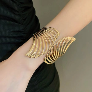 Close-up of golden hollow leaf cuff bracelet showing intricate feather design and texture