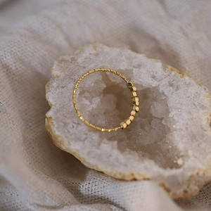 Vue détaillée d'une bague dorée à cubes hexagonaux sur un cristal géode naturel
