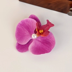 Detailed shot of pink orchid fabric hair claw with fiber texture and white pearl center