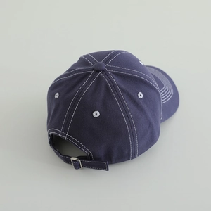 Detail view of the navy blue cotton baseball cap with white contrast stitching and strap