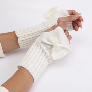Close-up of white knitted fingerless gloves with sweet bow detail and soft texture