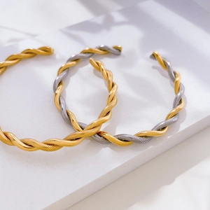 Detail view of twisted cable cuff bracelets in gold and silver finish on stone