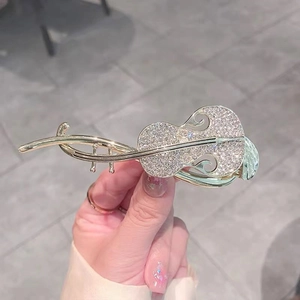Detailed view of a gold violin hair clip encrusted with sparkling rhinestones
