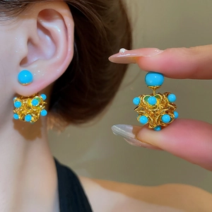 Detailed view of handmade resin hollow floral earrings with sky blue beads and gold plating