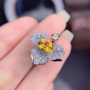 Macro shot of silver flower ring with yellow gemstone and pavé diamonds details