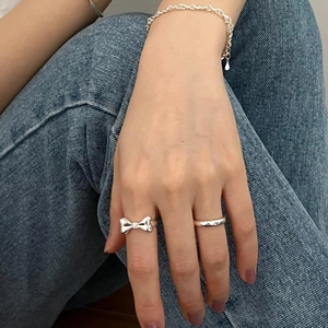 Close-up of 925 silver bow ring, minimalist band and chain bracelet on model